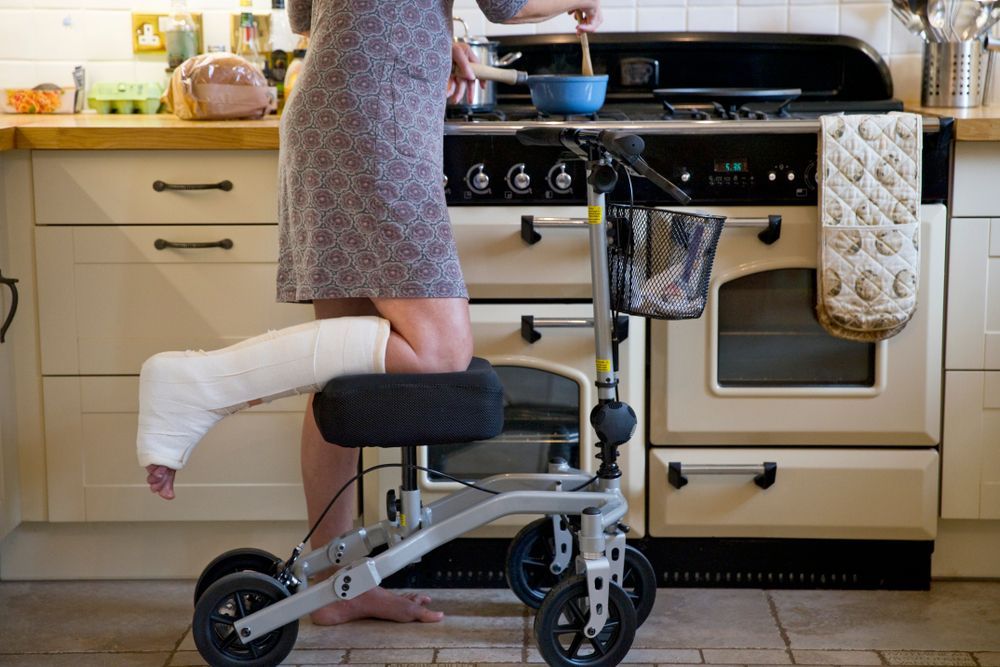 A Person With A Cast On Their Leg Is Sitting On A Knee Walker — Port Macquarie Physio & Pilates In Port Macquarie, NSW