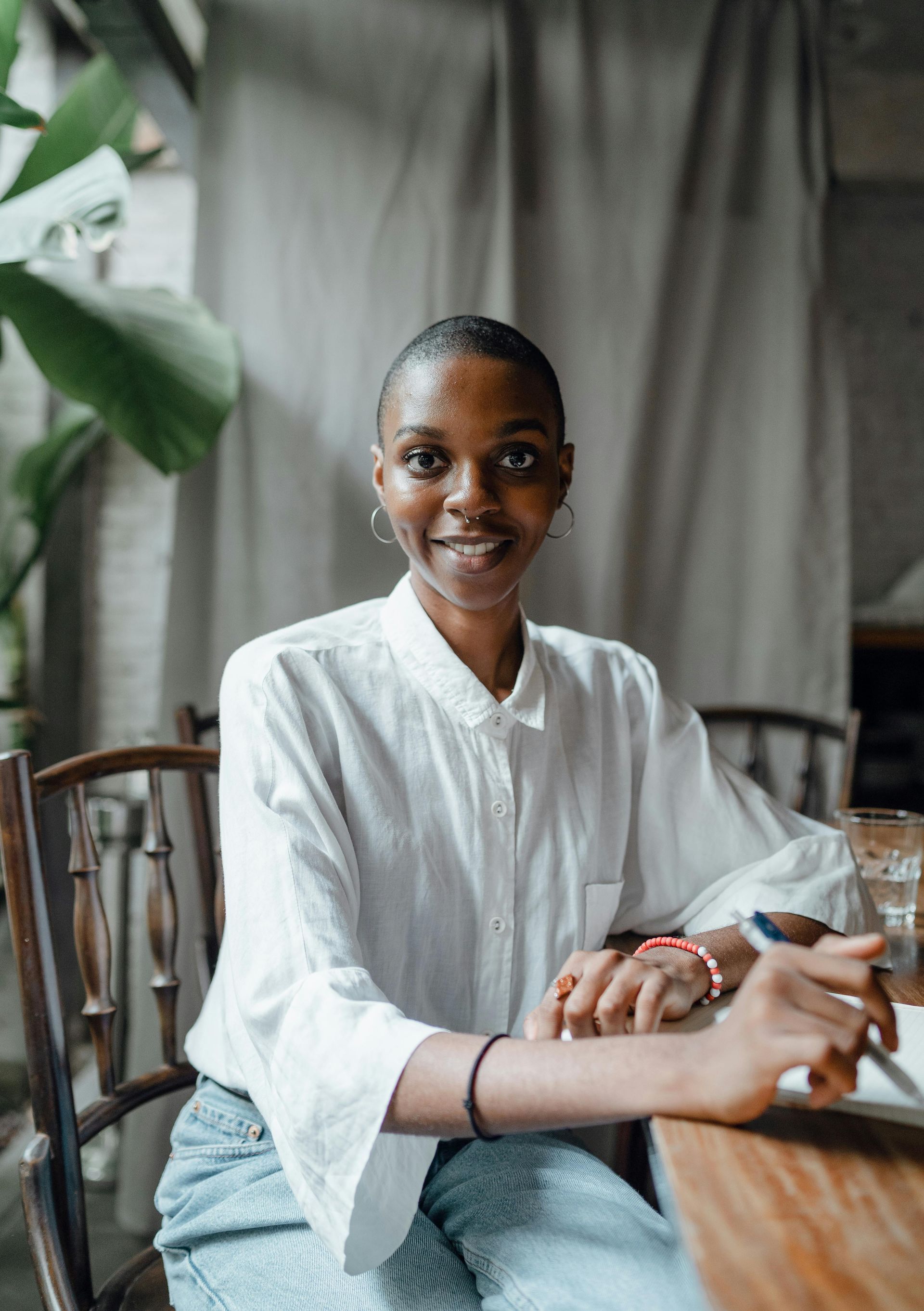 A woman is sitting at a table with a cell phone in her hand.
