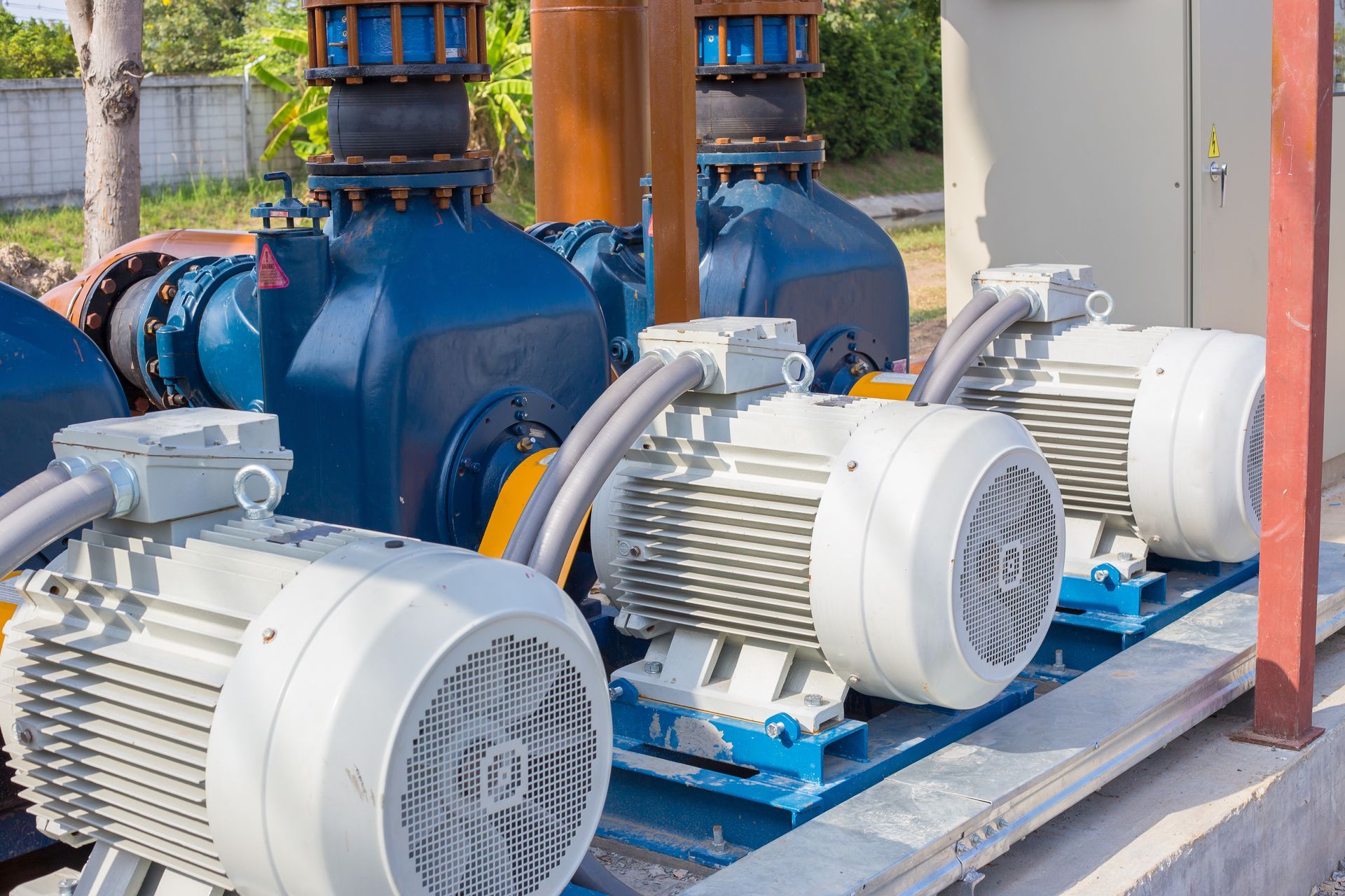 Blue industrial water pumps with white electric motors, outdoors.