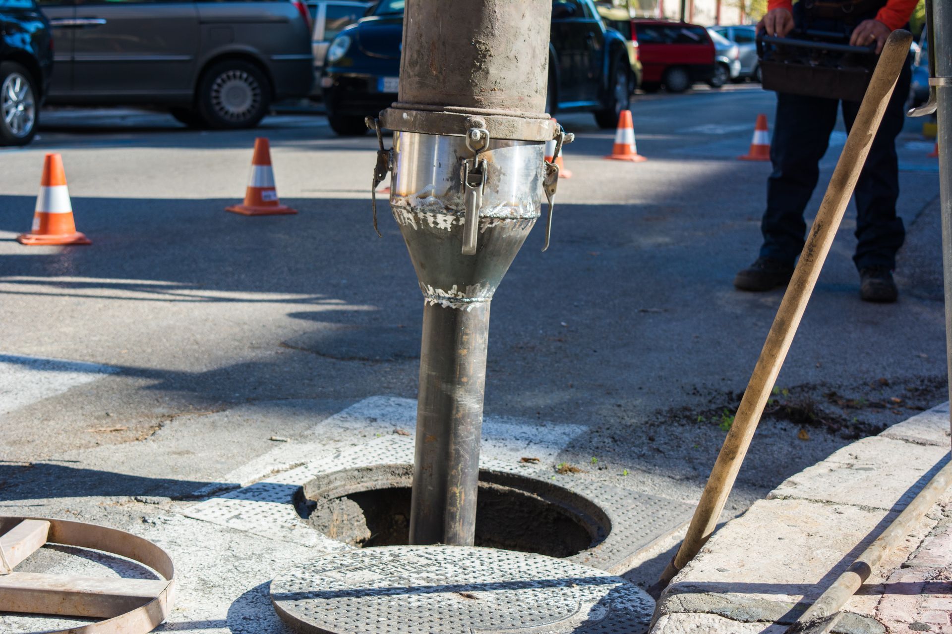 Concrete being poured into a manhole on a city street; a worker stands nearby. Concrete being poured into a manhole on a city street; a worker stands nearby.