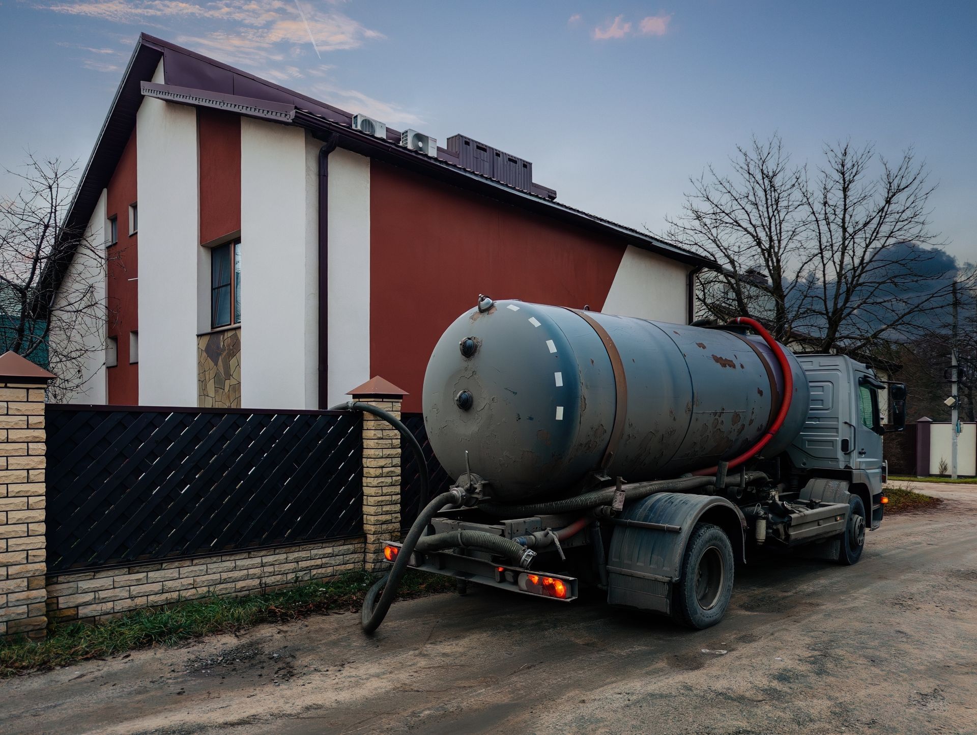 Tanker truck in front of a house, possibly servicing a septic system. Tanker truck in front of a house, possibly servicing a septic system.