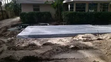Concrete slab in front of a house, surrounded by dirt and tire tracks.