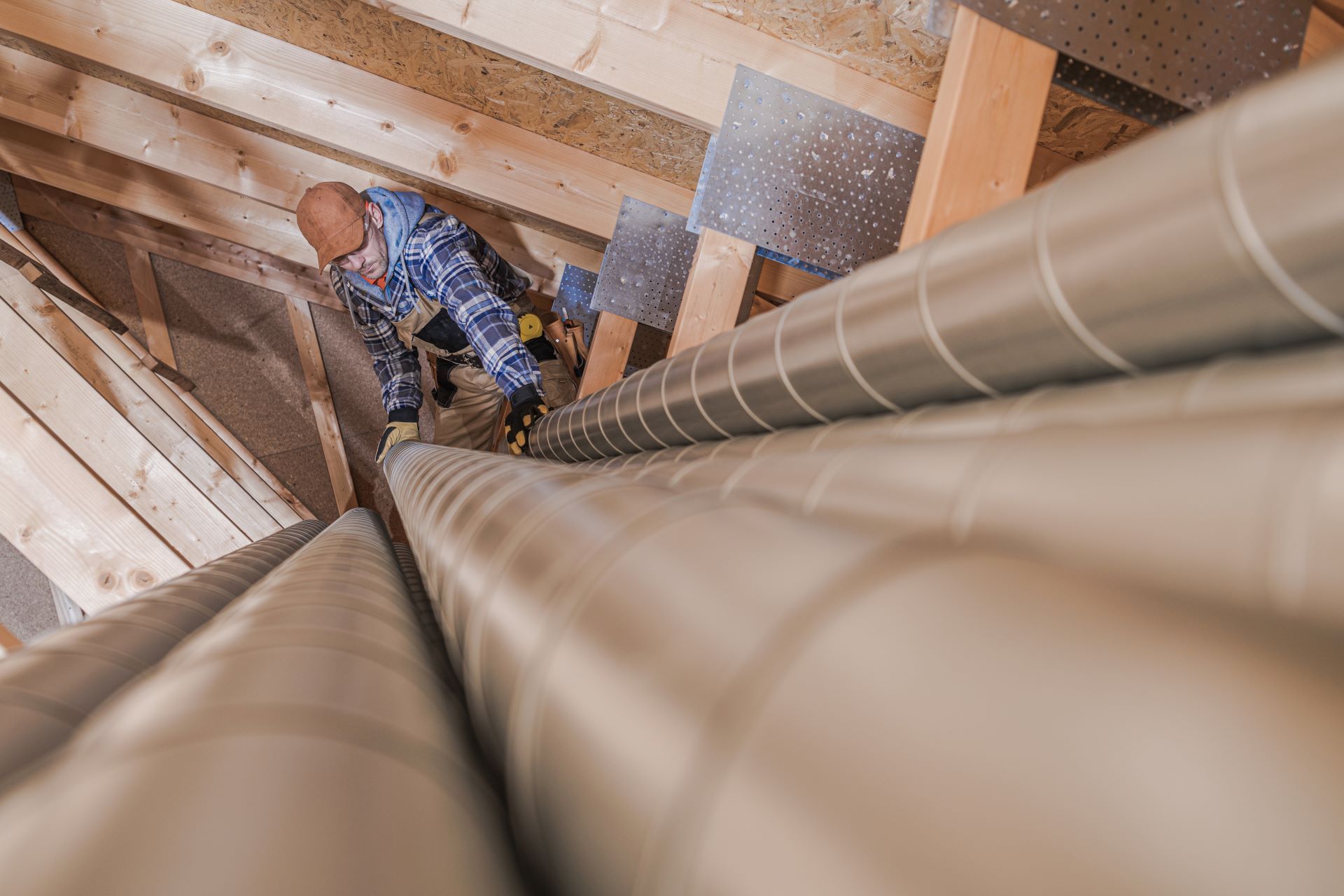 Man in attic installing HVAC ducts.