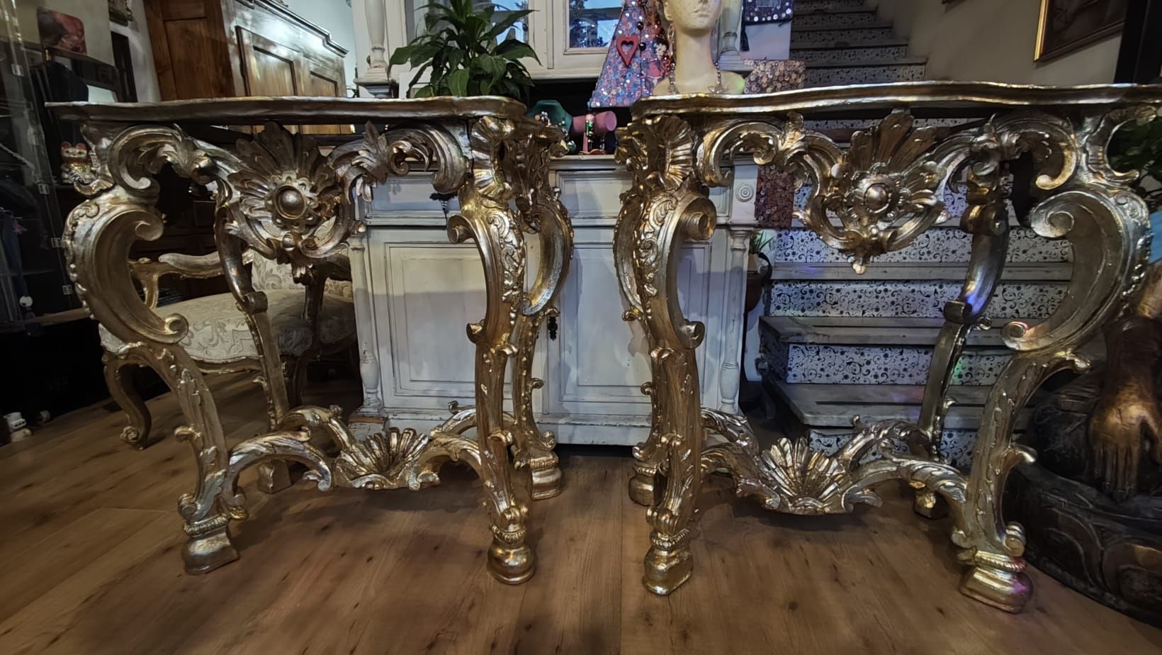 Orecchini a forma di fiore color oro con pietre preziose verdi al centro, appoggiati su pizzo nero.