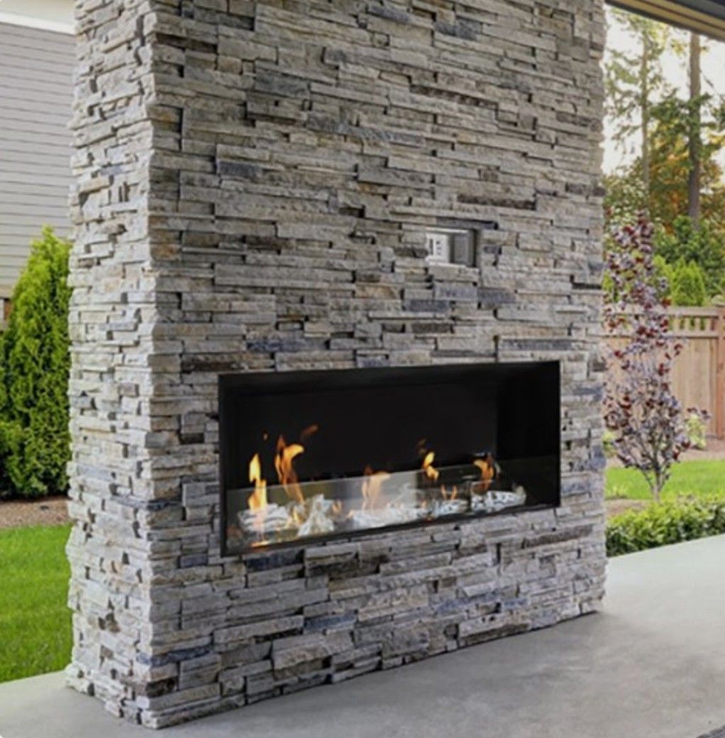 Modern outdoor stone fireplace with a burning gas flame on a patio