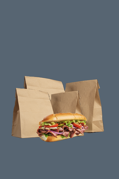 Op een stapel bruine papieren zakken ligt een broodje.