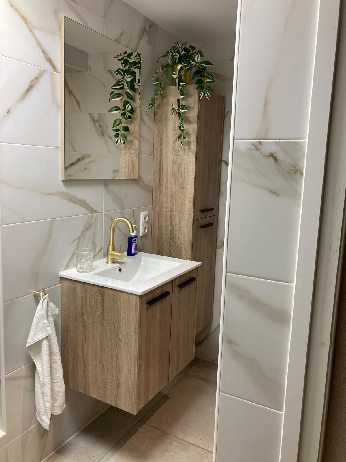 Een badkamer met wastafel, spiegel en kasten.