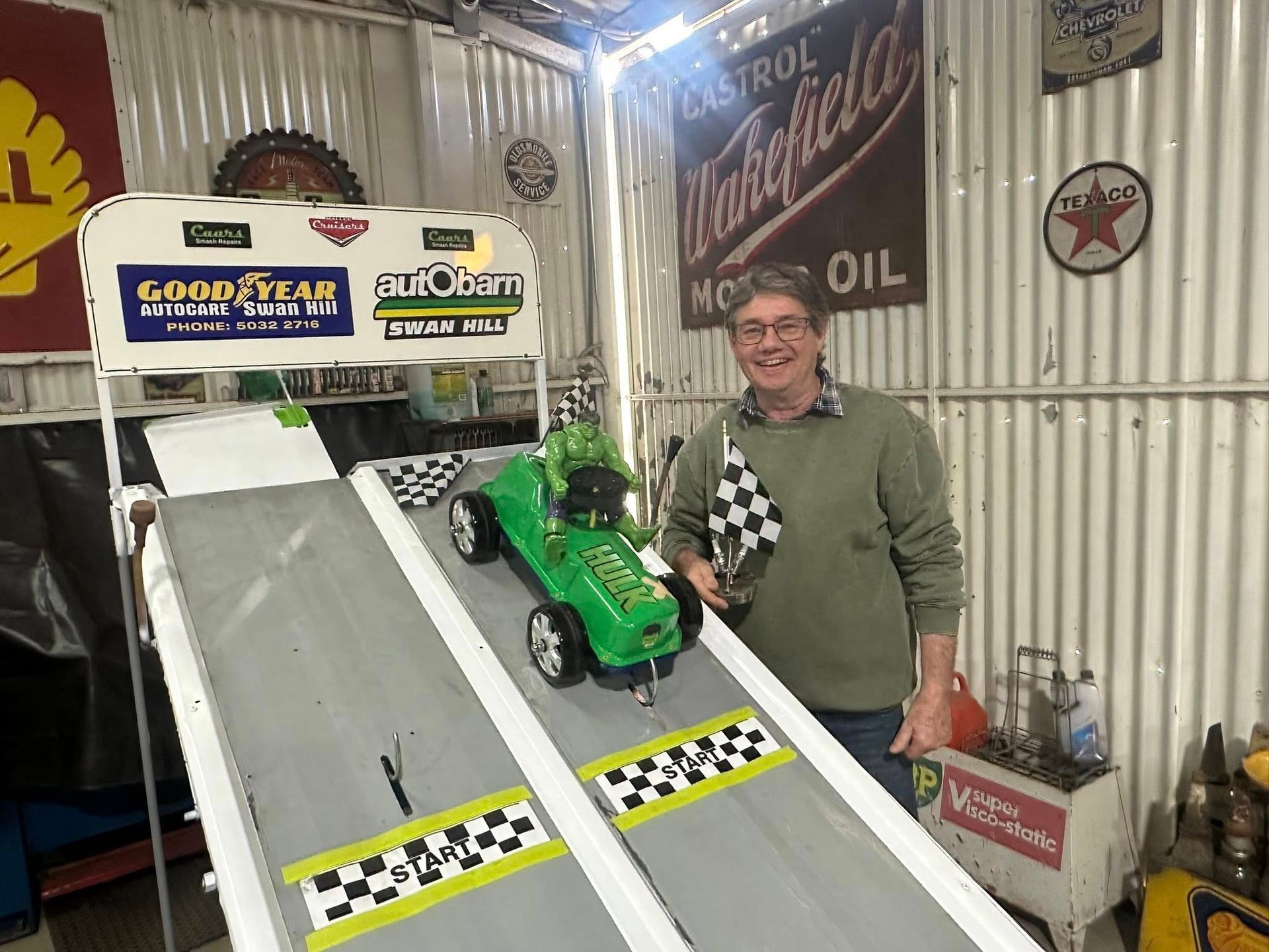 Man standing at the top of a racing ramp holding a checked flag 
