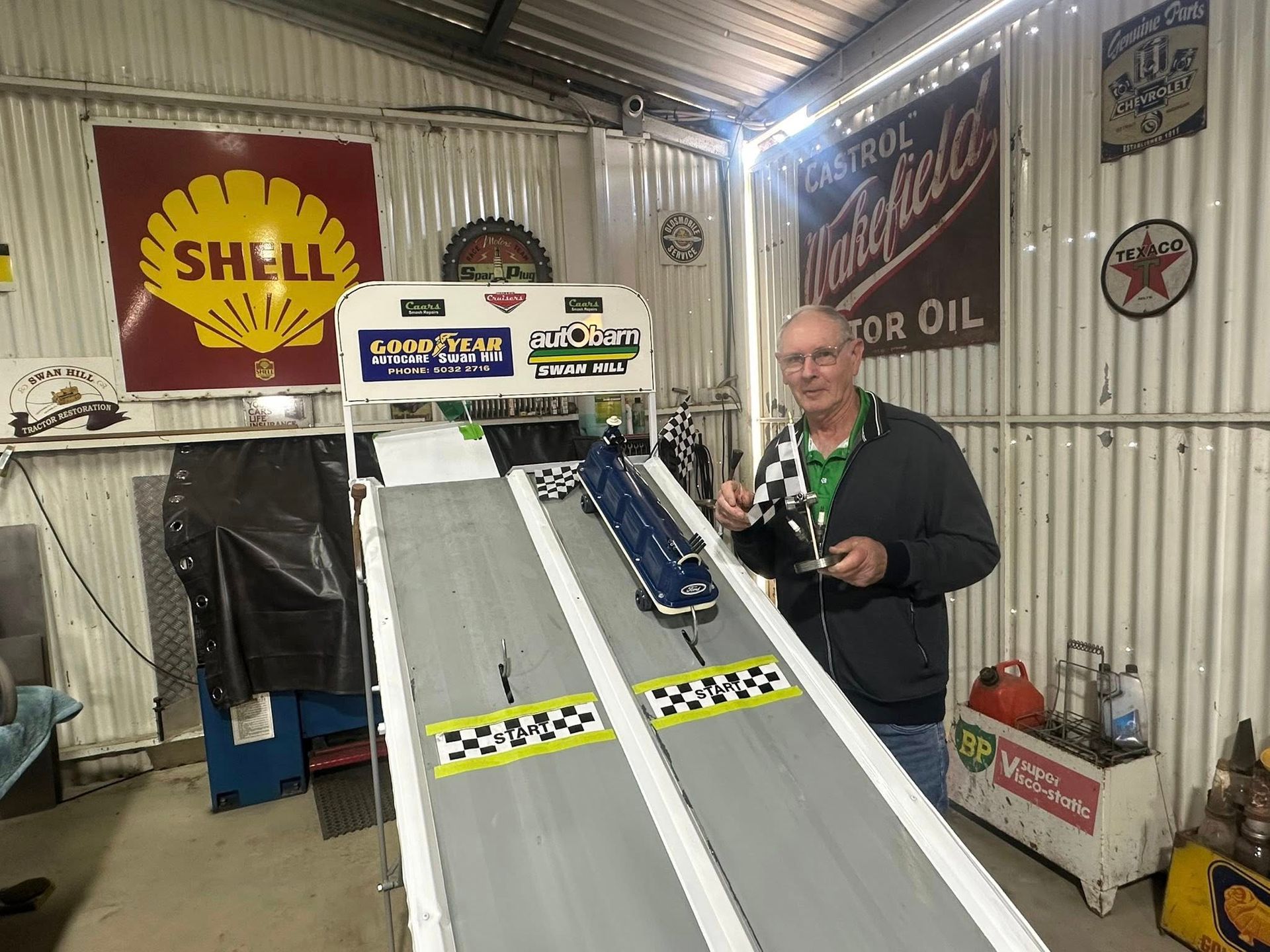 Man standing at the top of a car racing ramp holding a flag