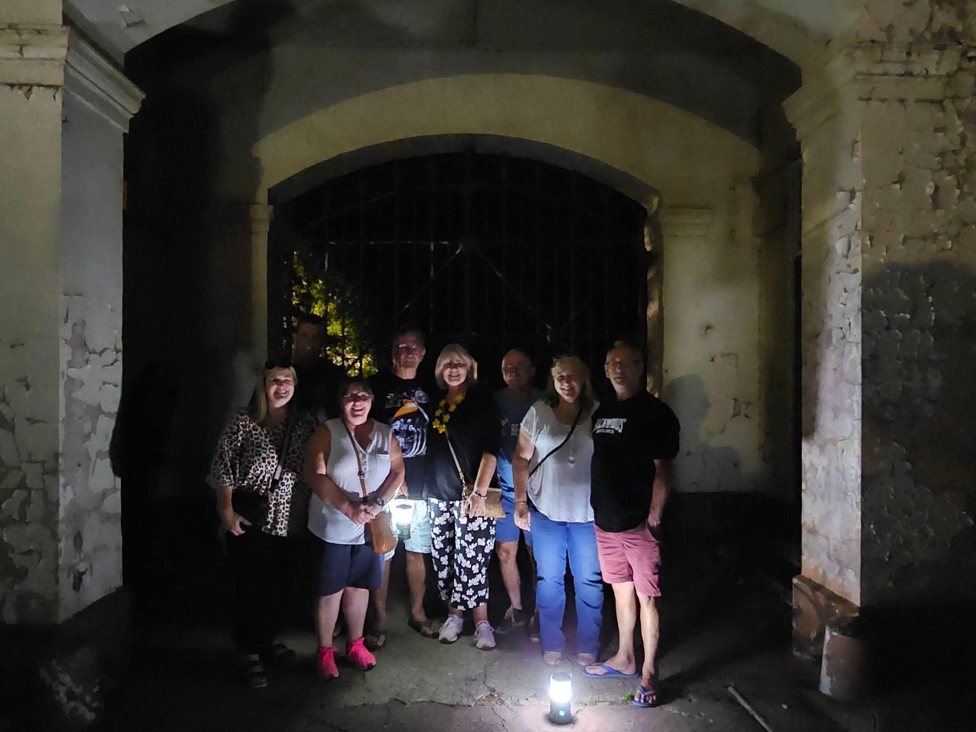 a group of people standing in a dark room their face lit by laterns
