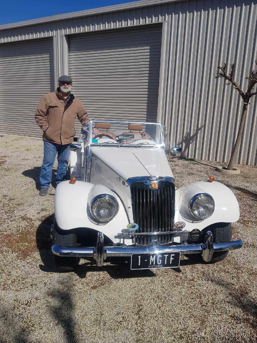 Man standing next to his white car