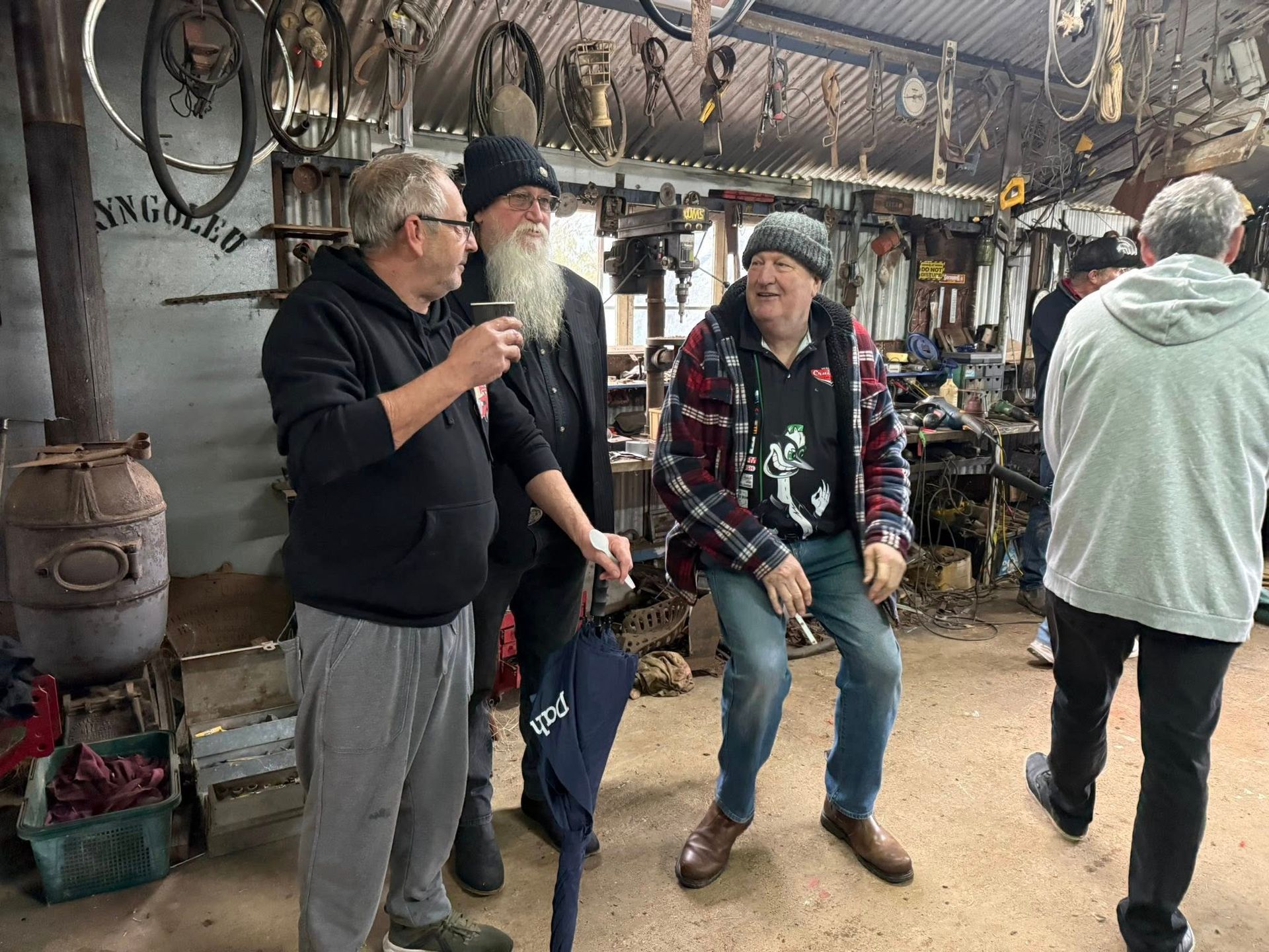 Three men stand around in a shed talking