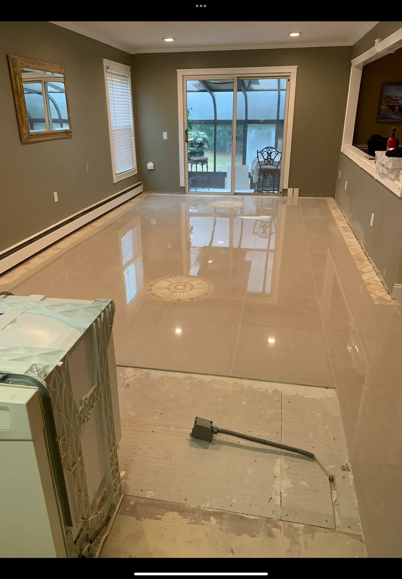 A living room with a sliding glass door and a broom on the floor.