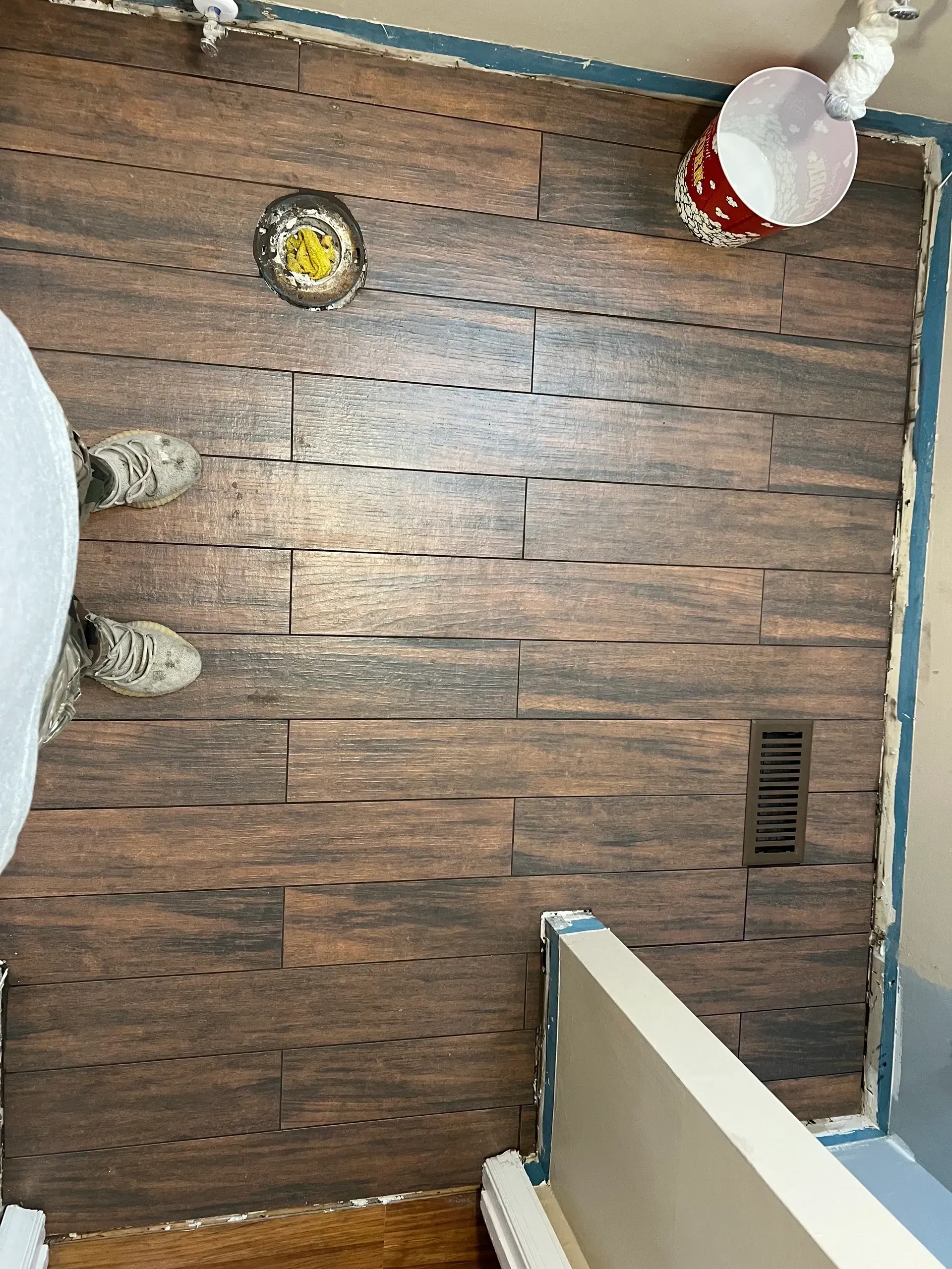 A person is standing on a wooden floor in a room.