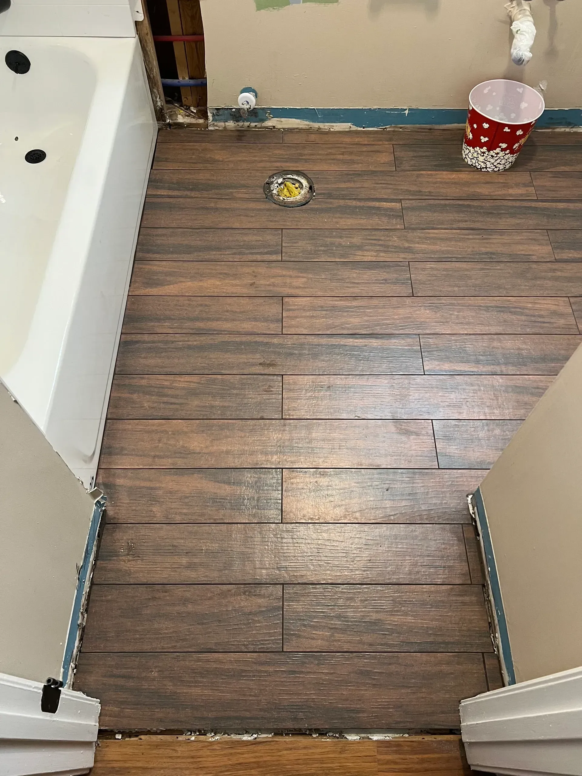 A bathroom with a wooden floor and a bathtub.