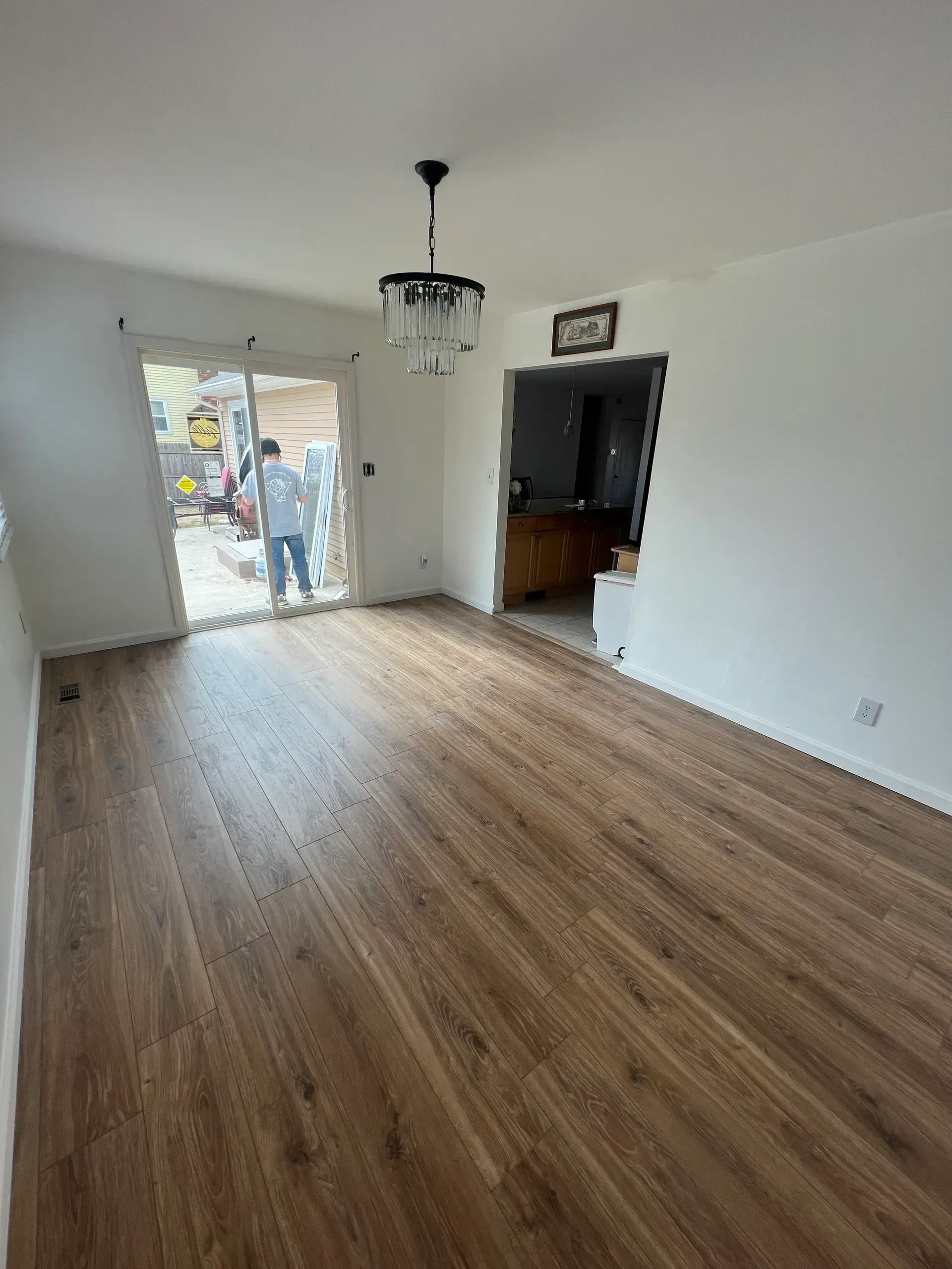 A living room with hardwood floors and a chandelier hanging from the ceiling.