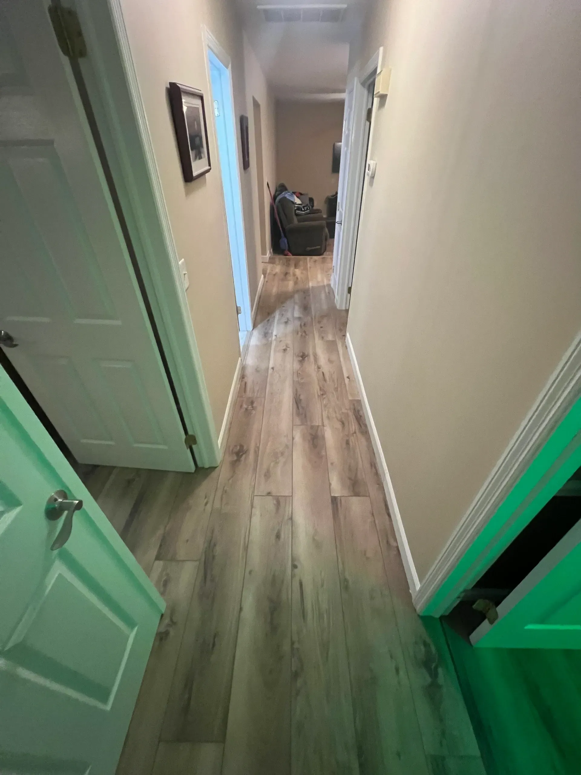 A hallway with hardwood floors and a green light on the wall.