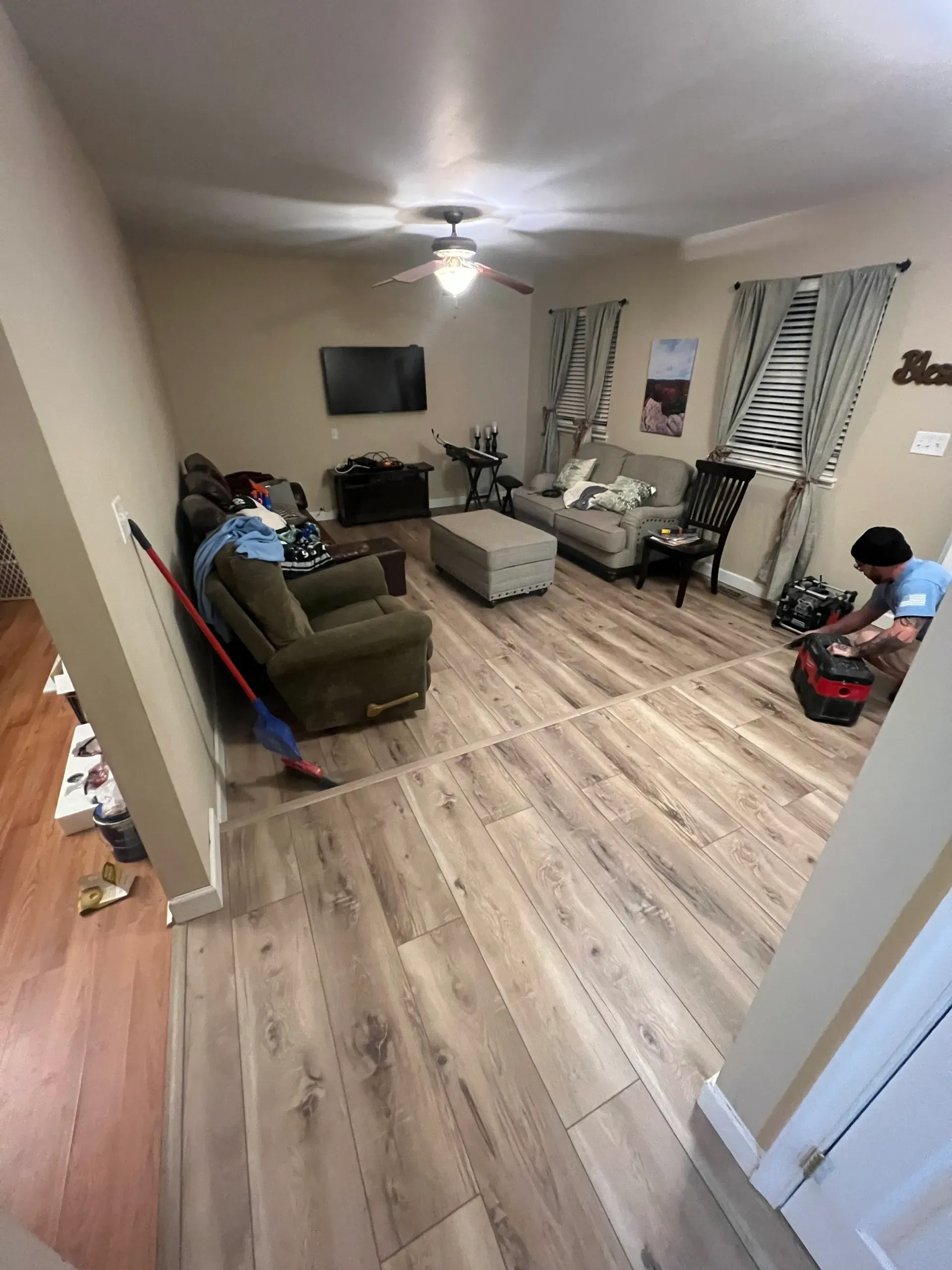 A living room with hardwood floors and a ceiling fan.