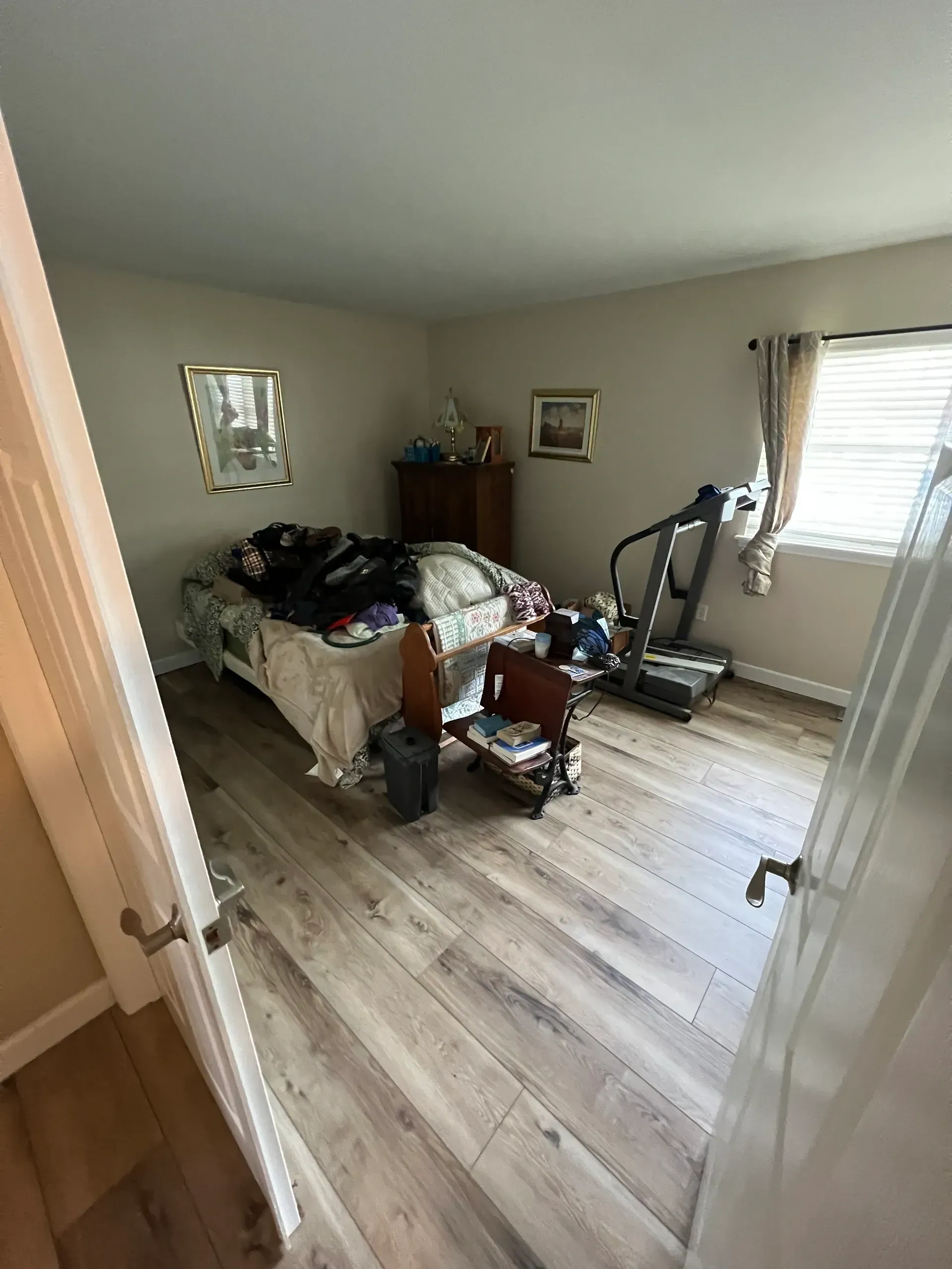 A bedroom with a bed and a treadmill in it.