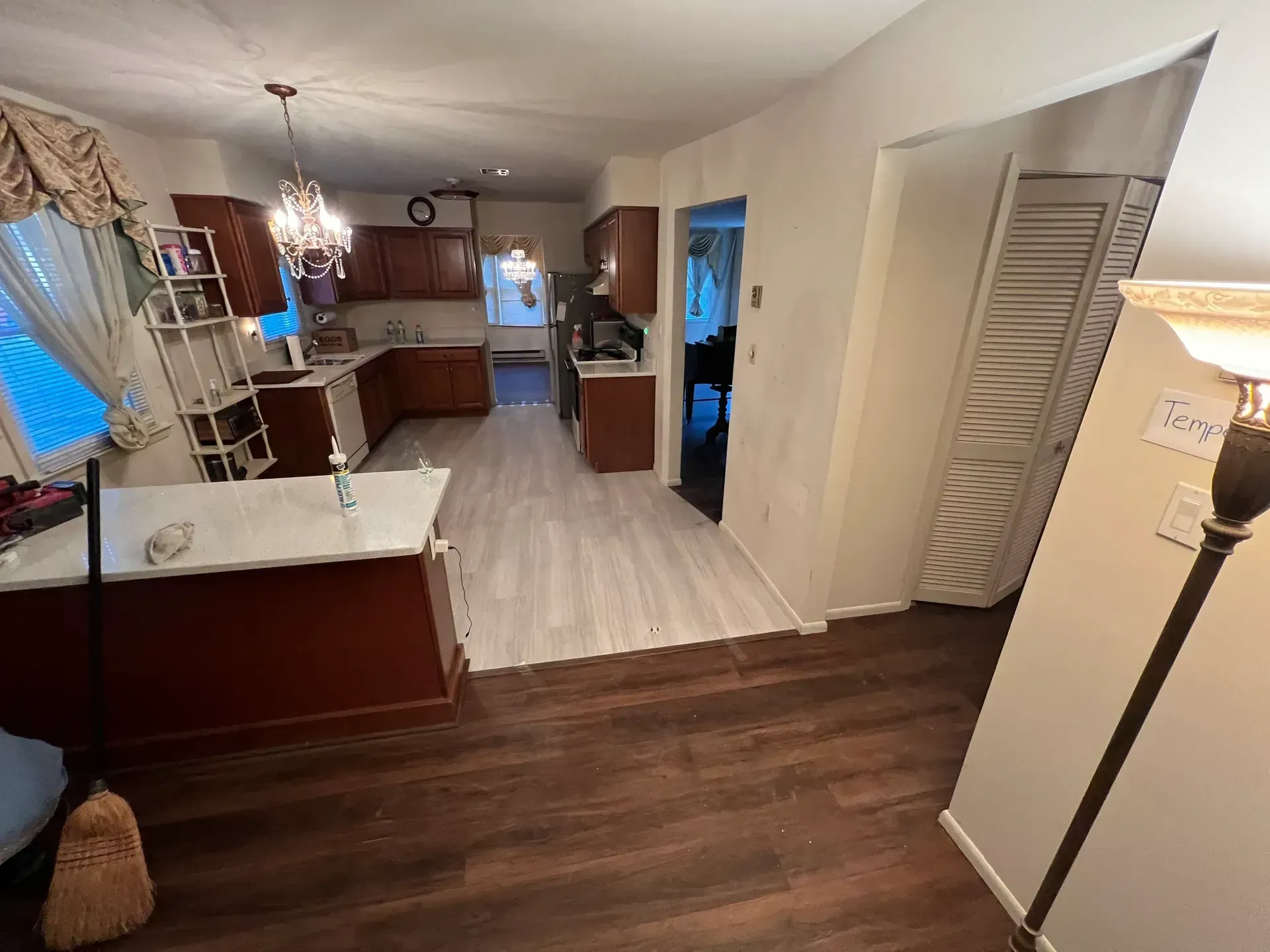 A living room with hardwood floors and a kitchen in the background.