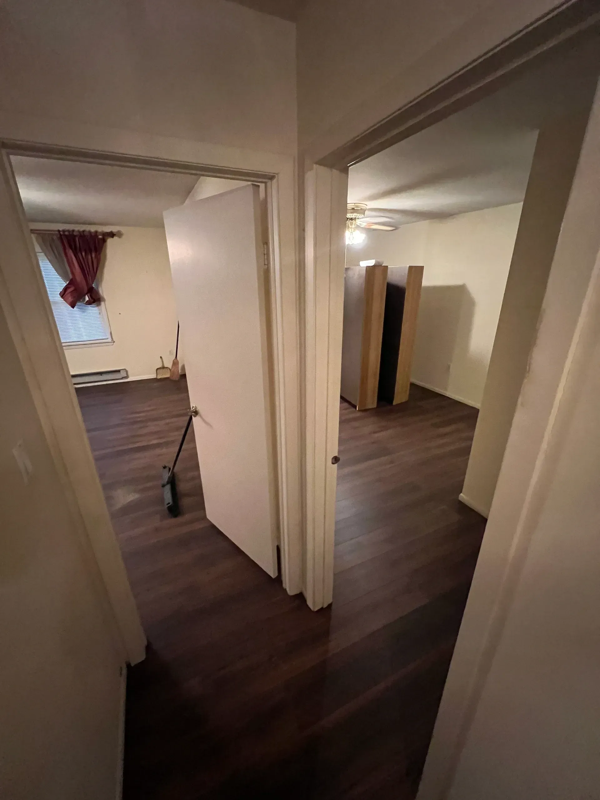 A hallway leading to a bedroom with hardwood floors and a ceiling fan.