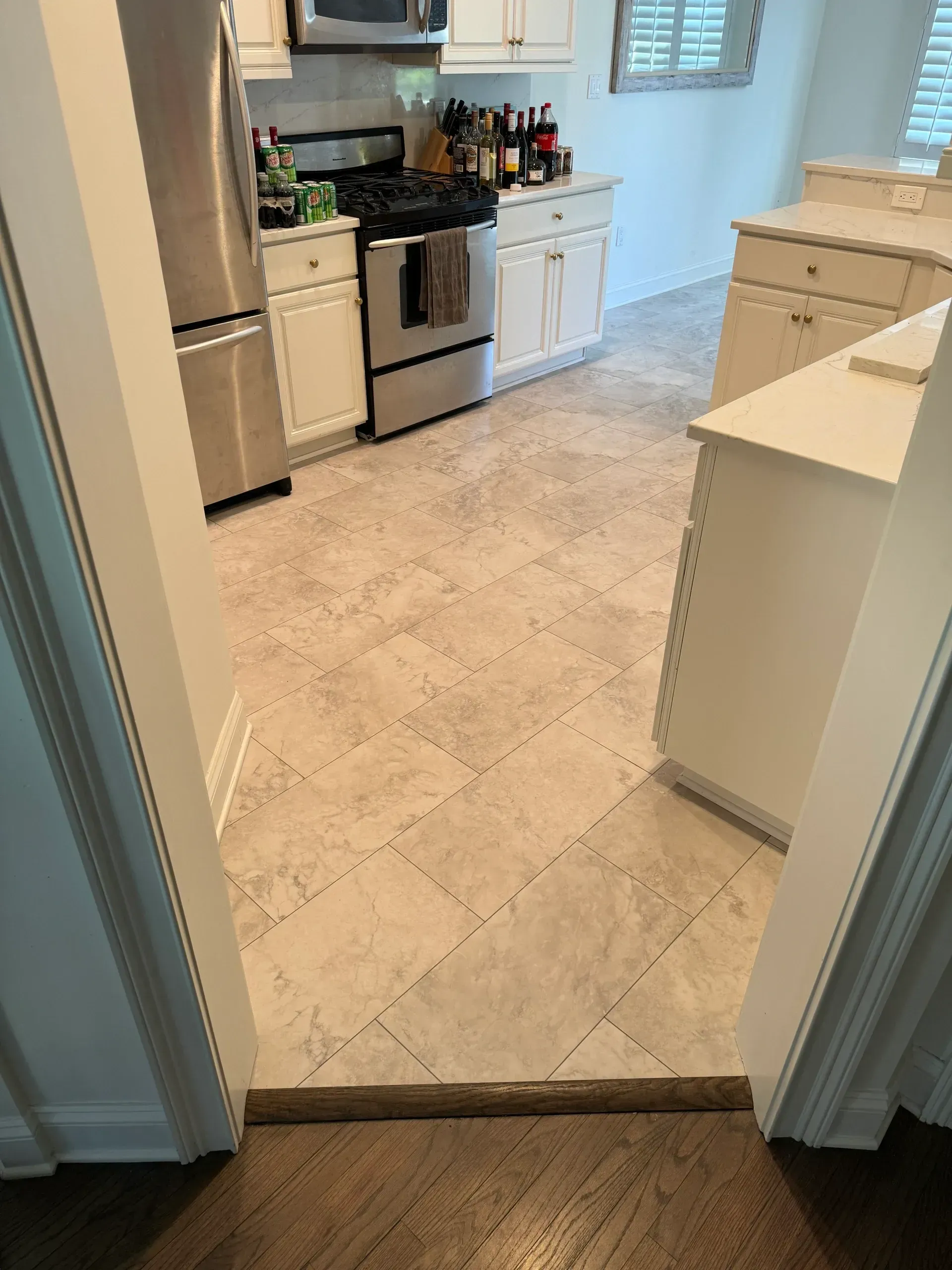 A kitchen with white cabinets , stainless steel appliances , and a tile floor.