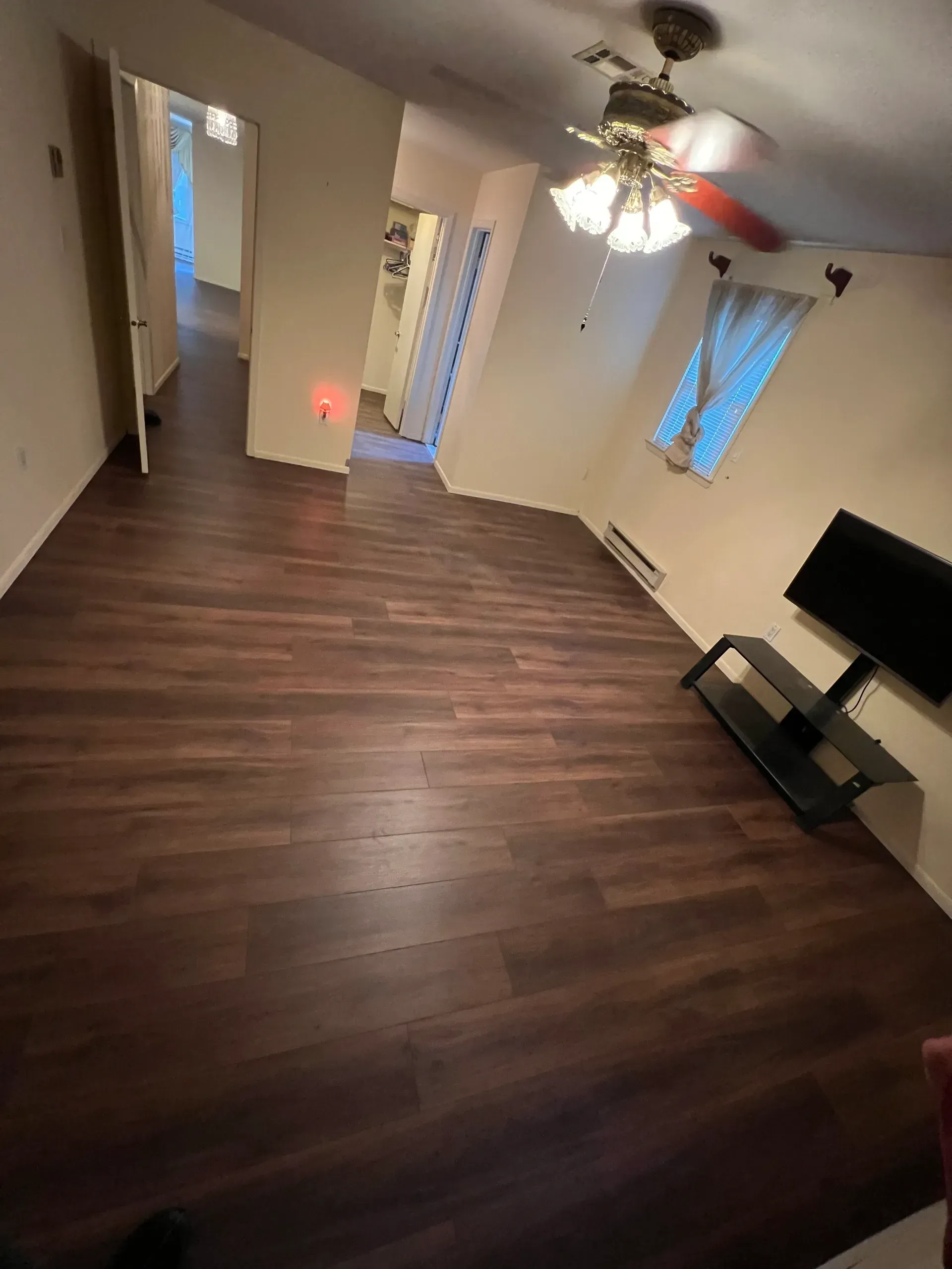 A living room with hardwood floors and a ceiling fan.