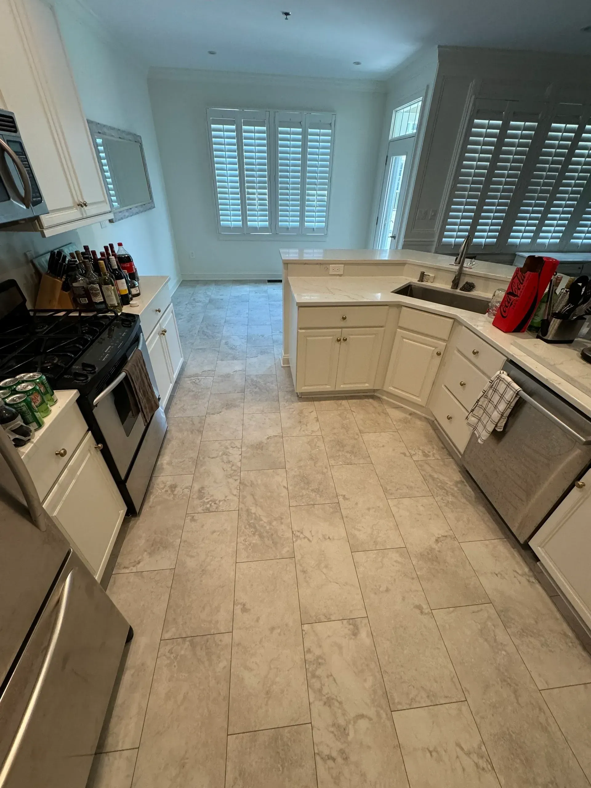 A kitchen with white cabinets , stainless steel appliances , a sink and a refrigerator.