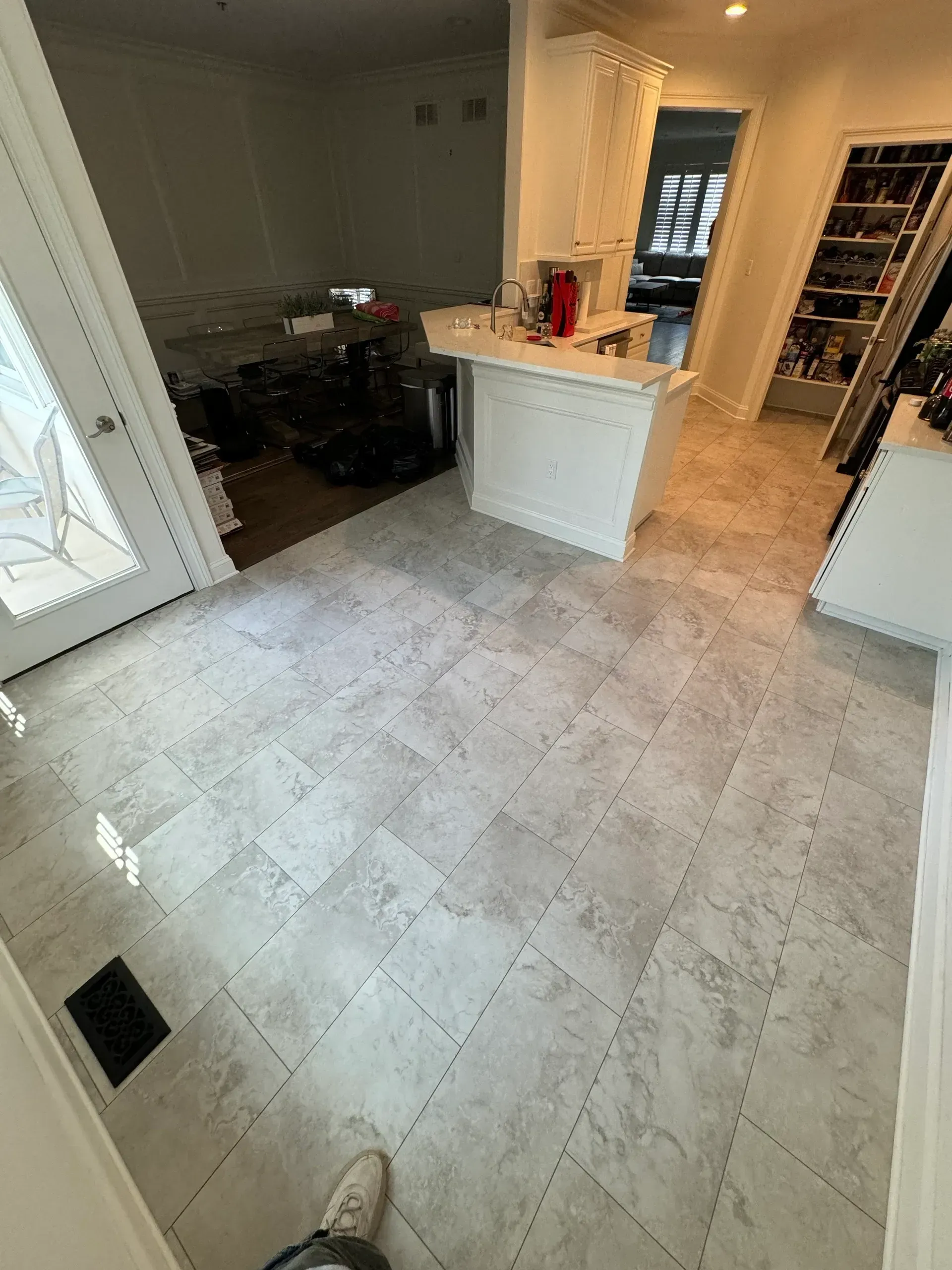 A kitchen with a gray tile floor and white cabinets.