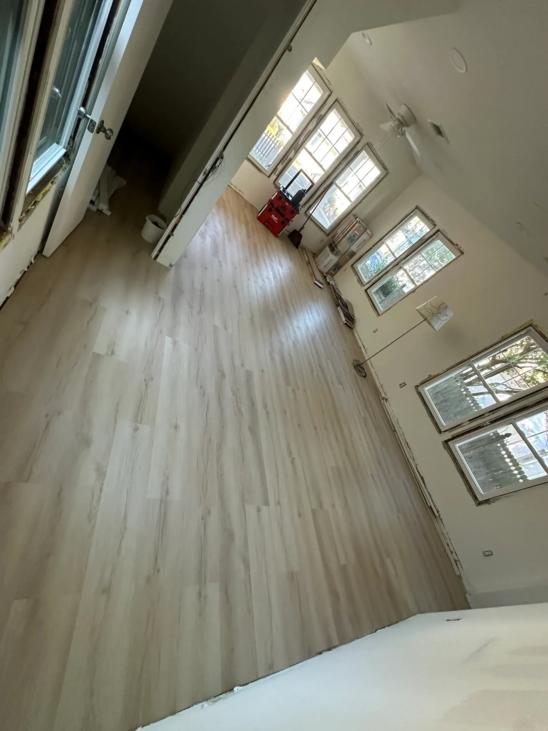 A large room with hardwood floors and lots of windows.