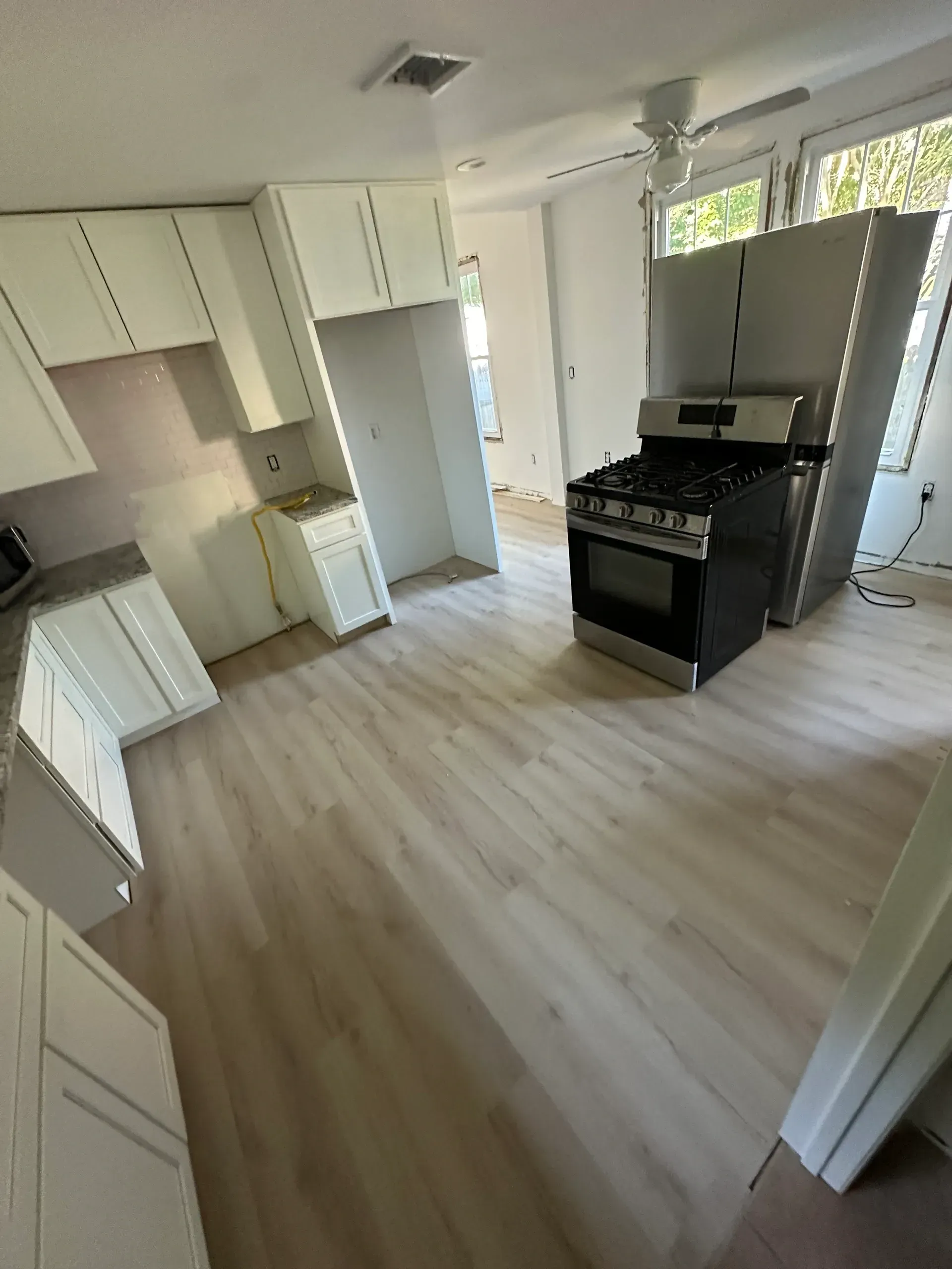 A kitchen with white cabinets , a stove and a refrigerator.