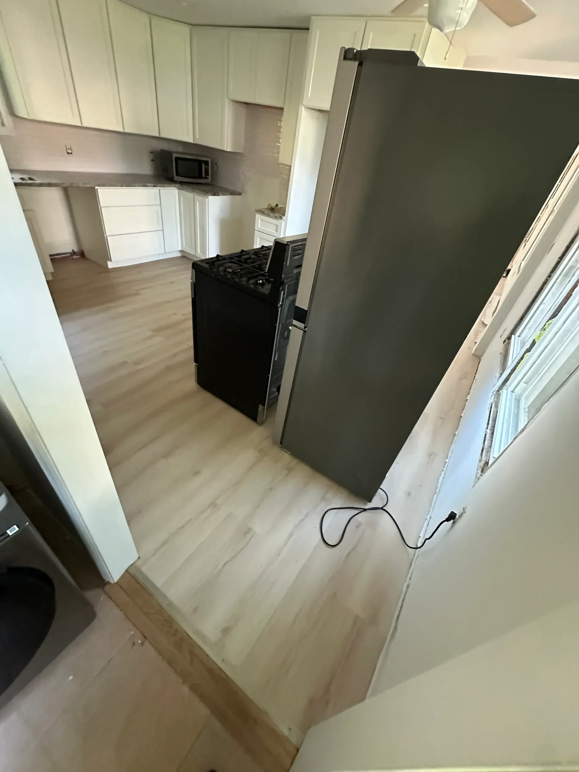 A kitchen with white cabinets and a black refrigerator