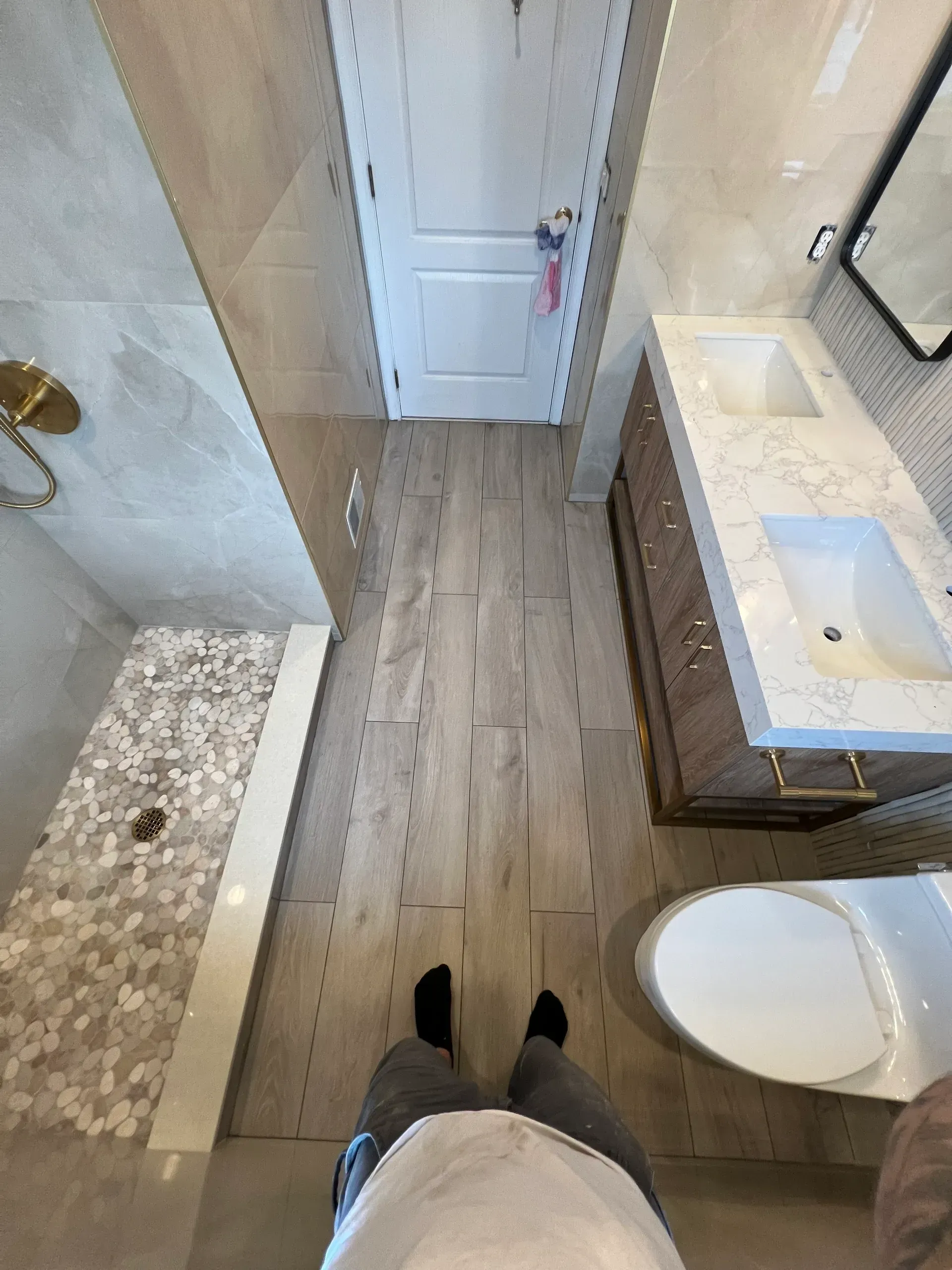 A person is standing in a bathroom next to a toilet and sink.