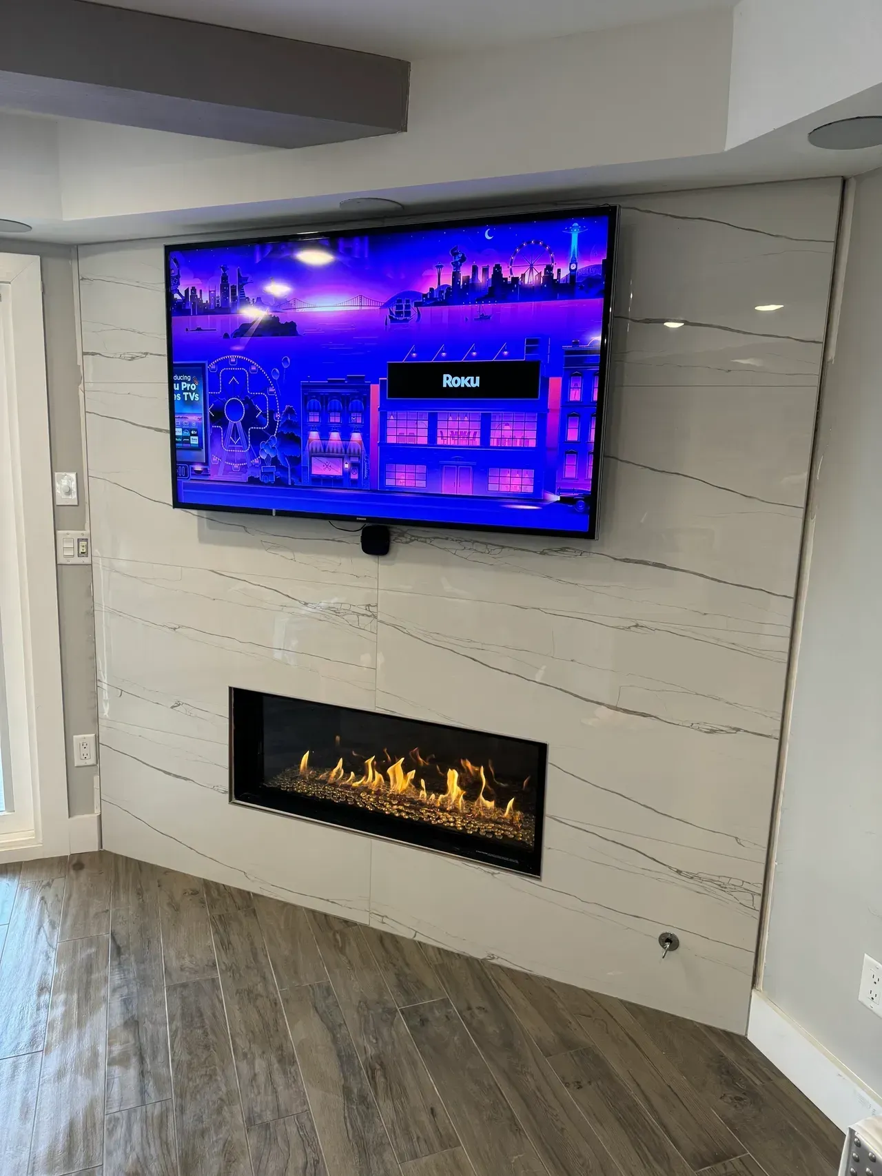 A living room with a fireplace and a flat screen tv hanging on the wall.