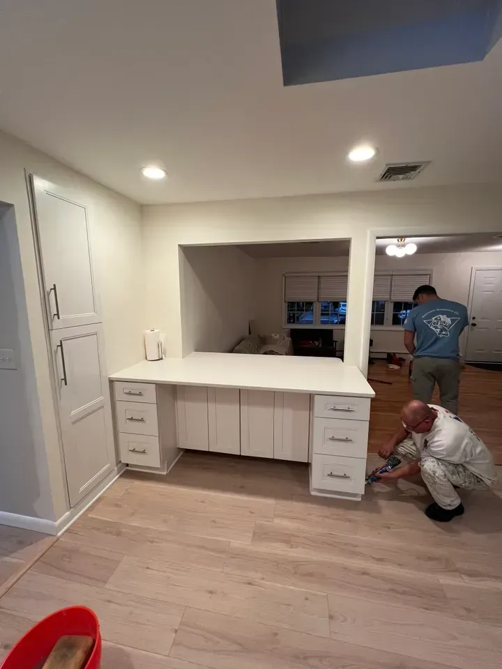 A man is kneeling down in front of a desk in a room.