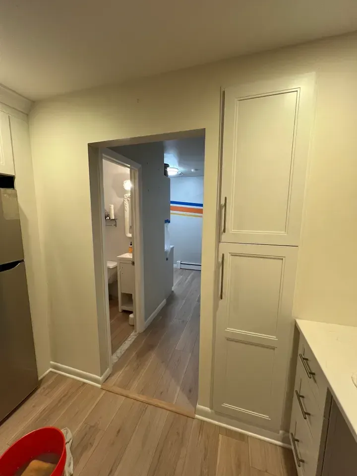 A kitchen with a refrigerator , cabinets , and a red bucket.