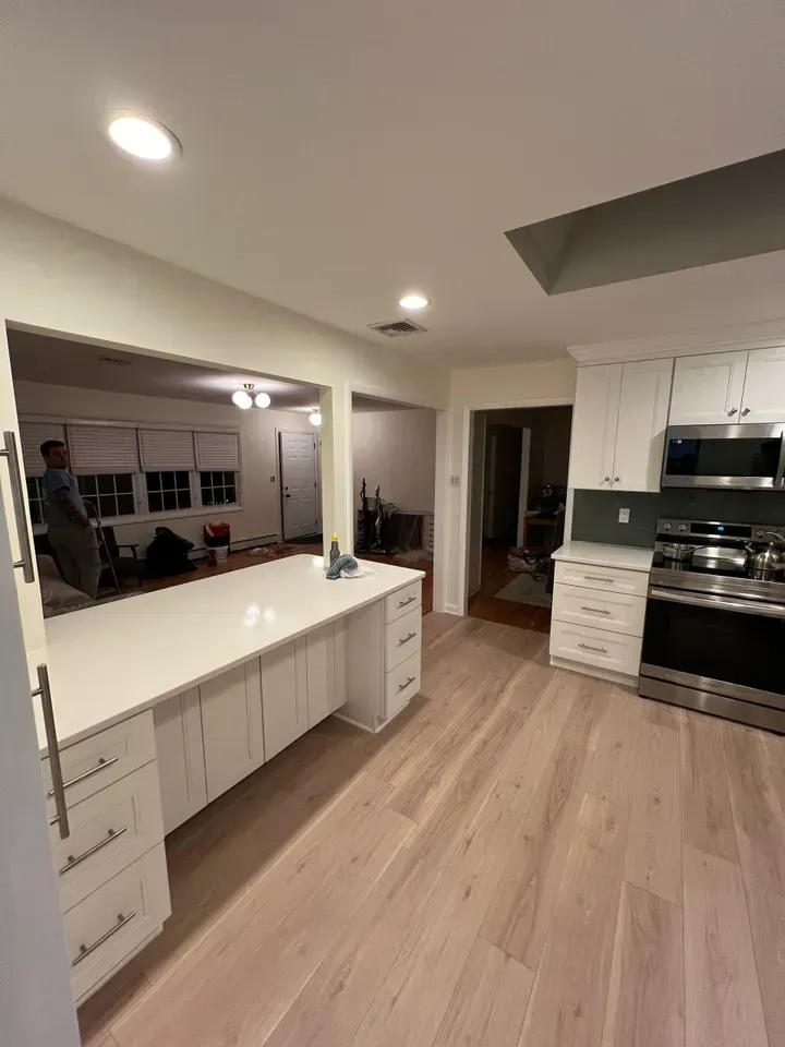 A kitchen with white cabinets , stainless steel appliances , and hardwood floors.