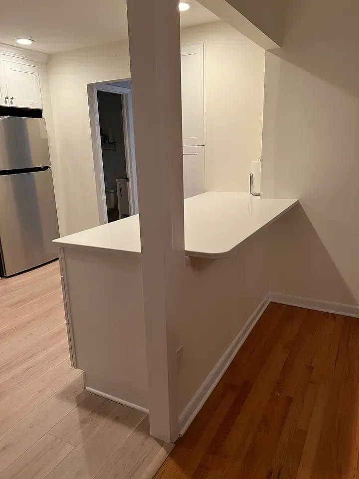 A kitchen with hardwood floors and a stainless steel refrigerator.