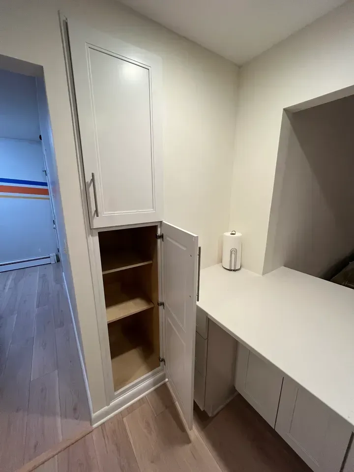 A room with a desk and a cabinet with the door open.