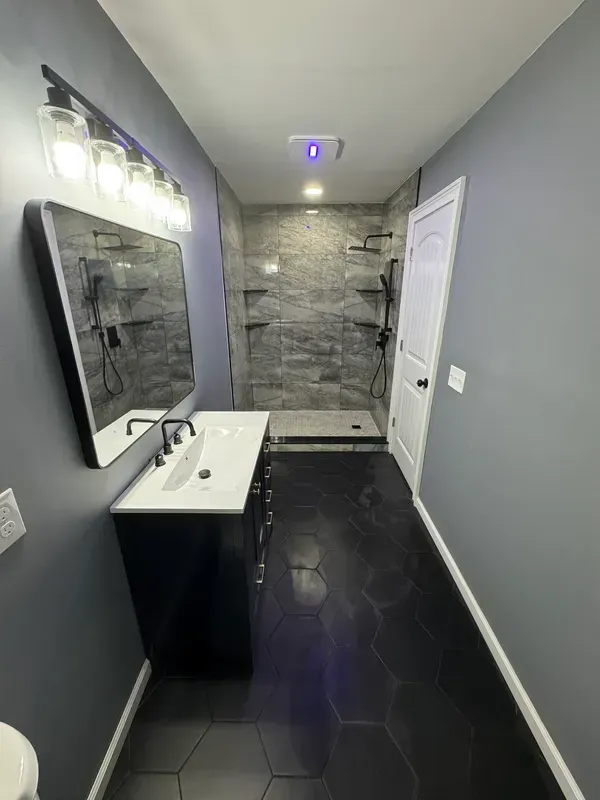 A bathroom with a sink , mirror , and walk in shower.