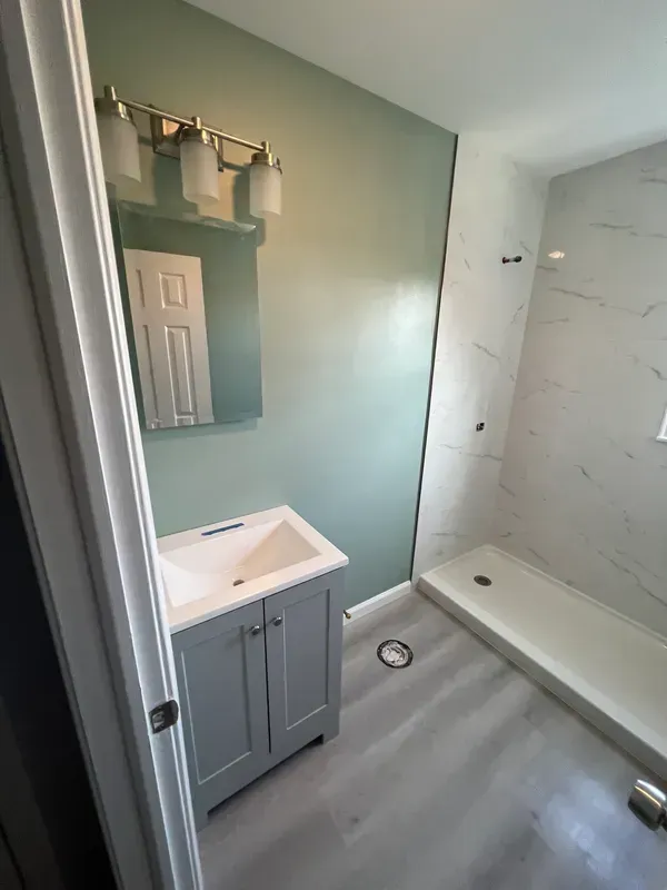 A bathroom with a sink , mirror and shower.