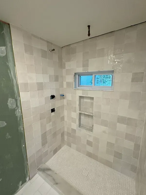 A bathroom with a walk in shower and a window.