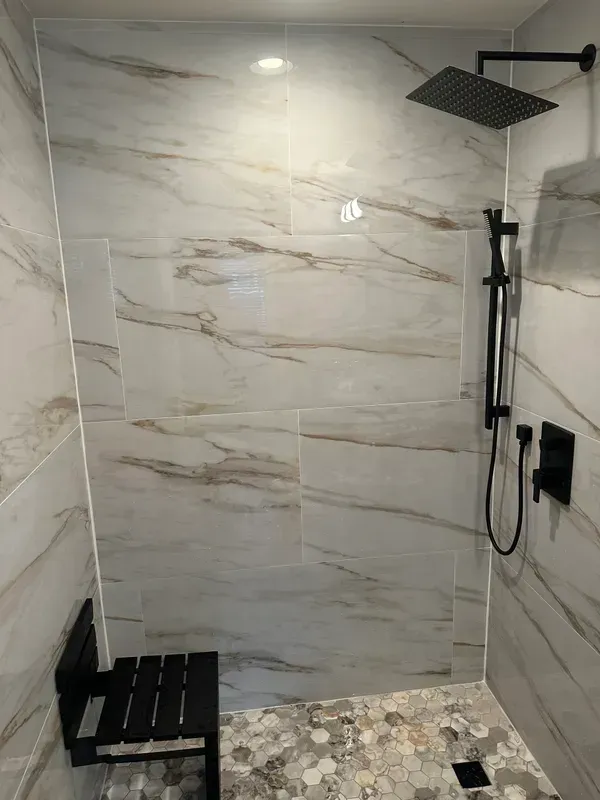 A bathroom with a walk in shower and a black shower head.