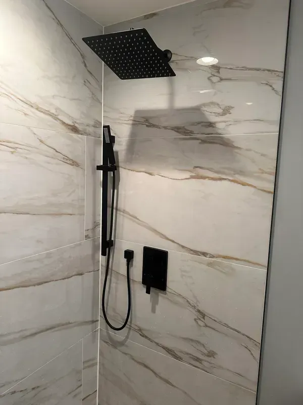 A shower with a black shower head and a black shower head.