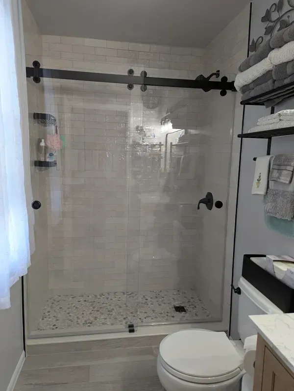 A bathroom with a sliding glass shower door and a toilet.