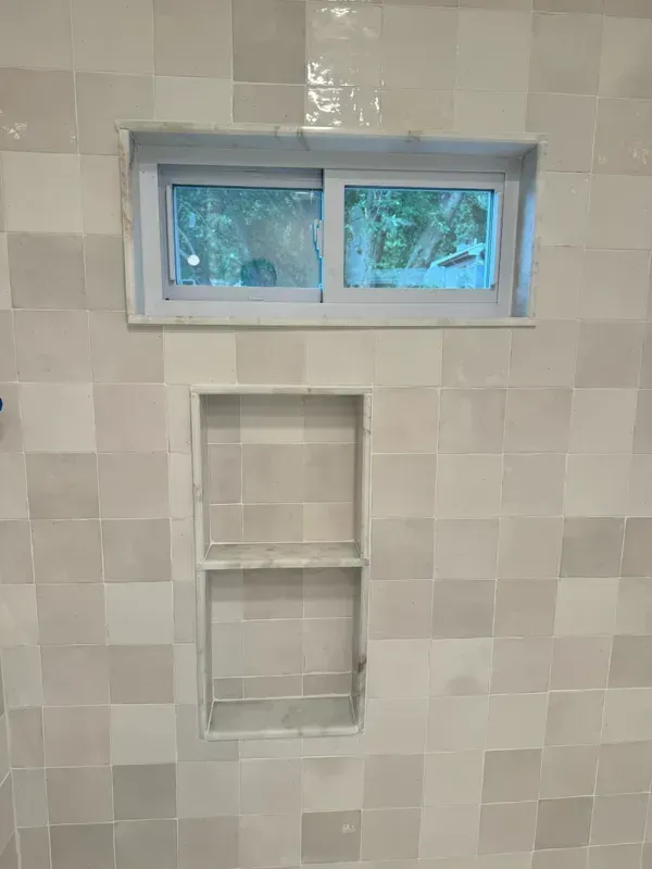 There is a window in the shower with a sliding glass door.