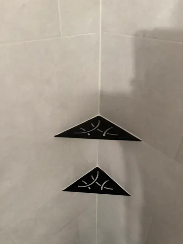 Two black triangles are hanging on a white tiled wall.