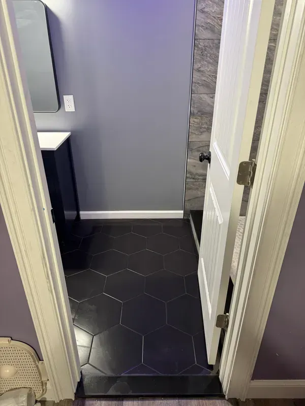 A bathroom with black tiles , a sink and a mirror.