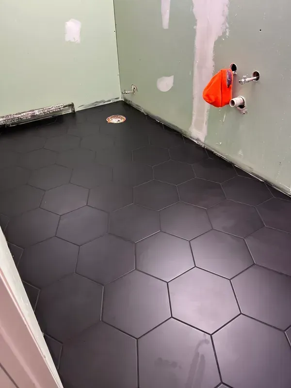 A bathroom with a black tile floor and green walls.
