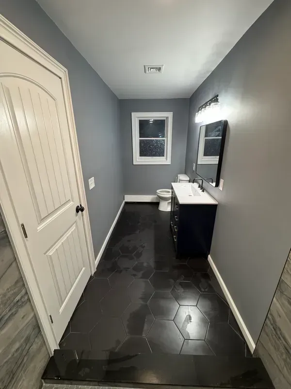 A bathroom with a sink , toilet and mirror.